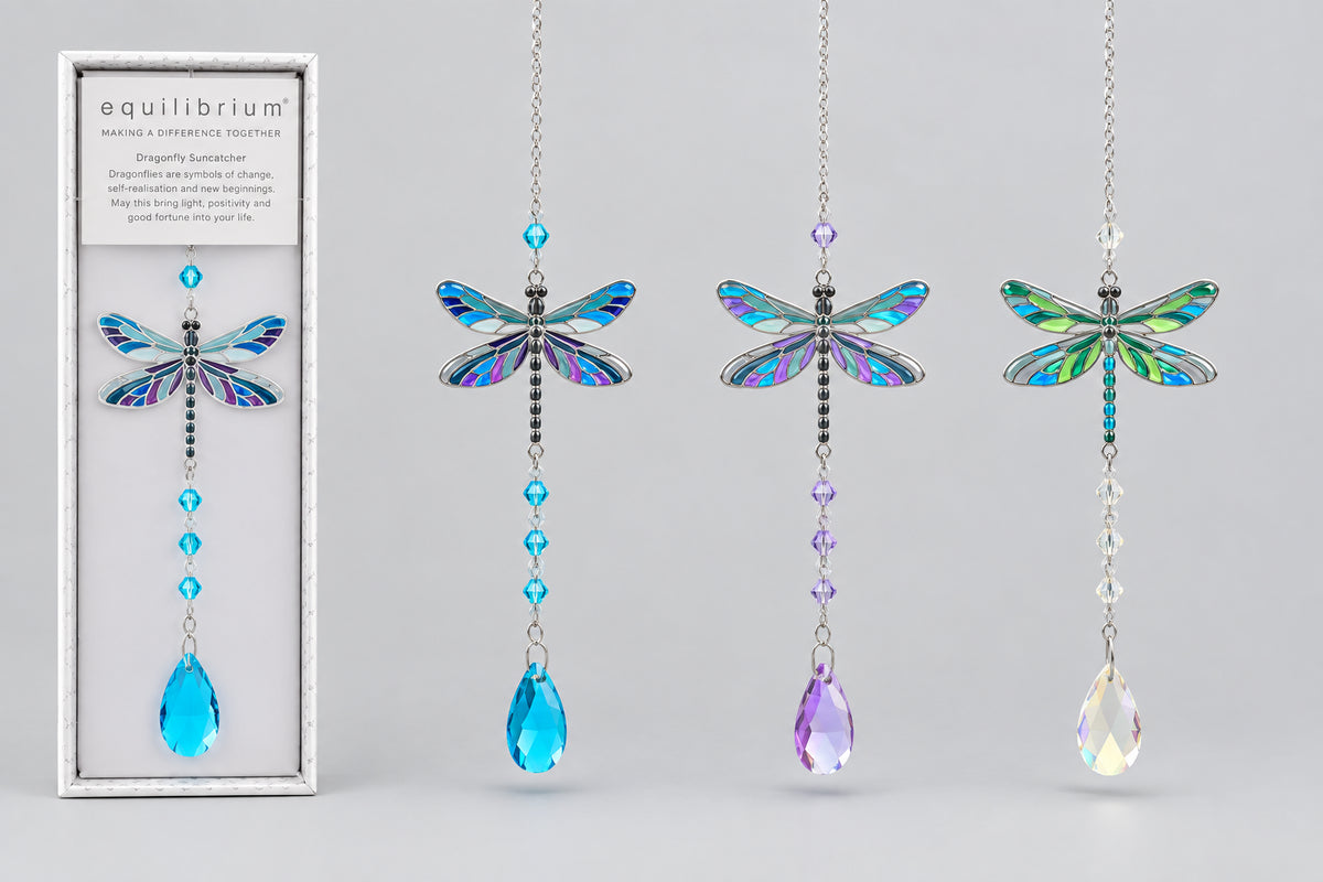 Three hanging dragonfly suncatchers with iridescent wings and dangling teardrop beads are shown beside their retail box. The wings display shifting blue, green, and purple tones, and the beads are blue, purple, and clear.