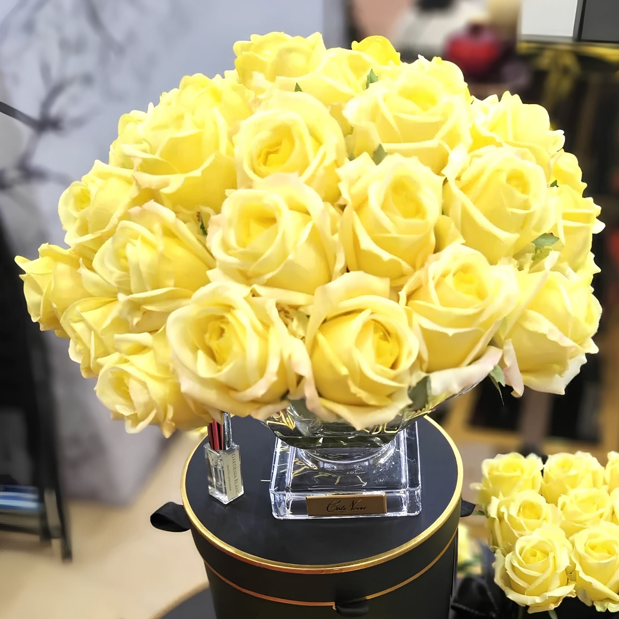 Close-up of Côte Noire Luxury Centrepiece Yellow rose buds in crystal-clear gel with gold badge detail